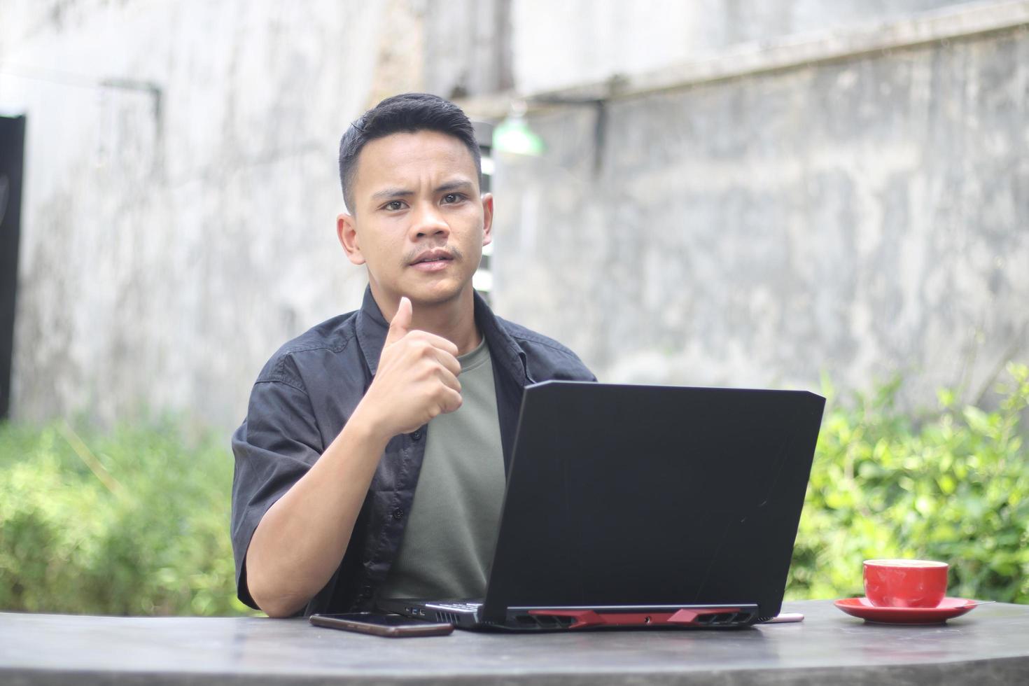 Attractive young Asian man using laptop in co-working space with happy face photo