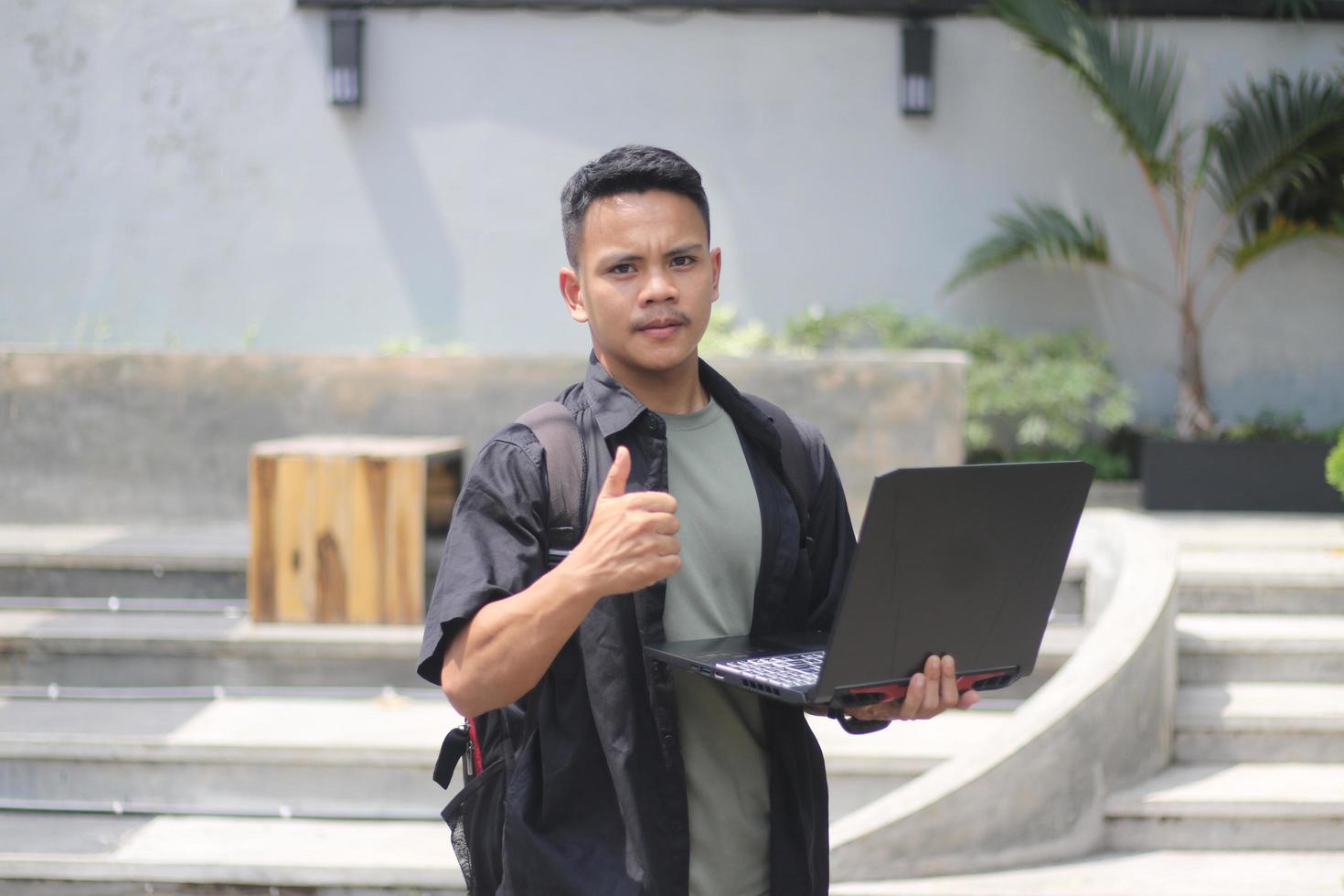 Attractive young Asian man using laptop in co-working space with happy face photo