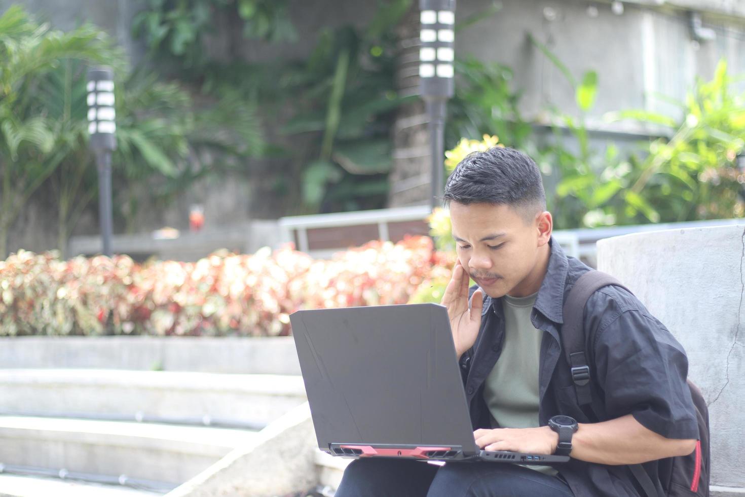 Attractive young Asian man using laptop in co-working space with happy face photo