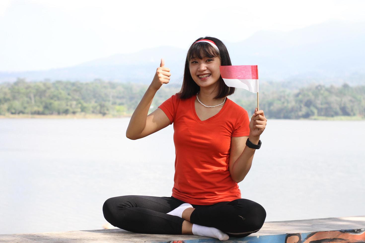 beautiful young asian woman carrying the indonesian flag with a cheerful face photo