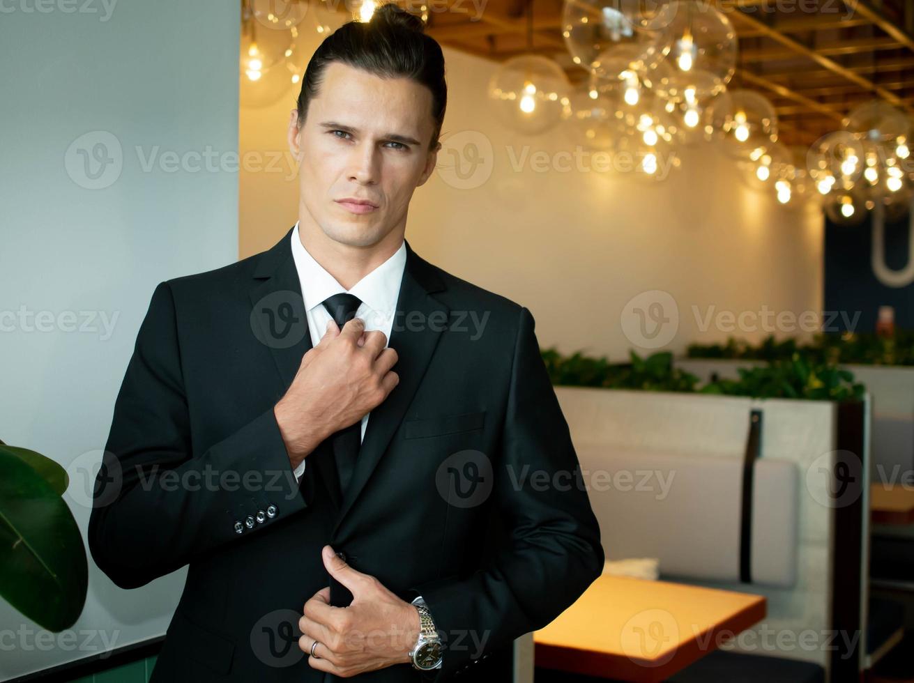 businessman male man wear black suit tie standing young adult portrait smart adult manager professional office company indoor looking at camera white cauasian work job occupation career handsome boss photo