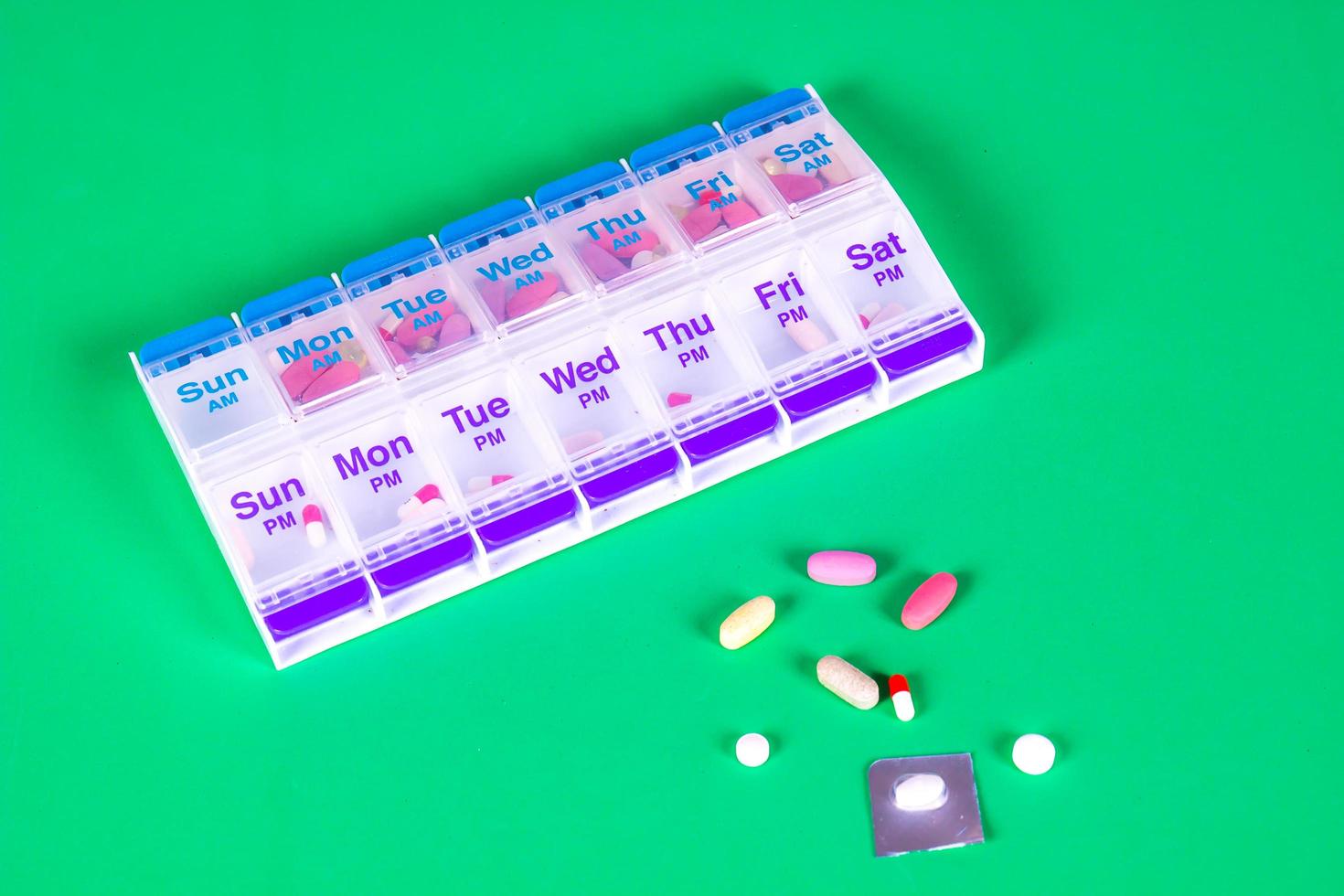 Colorful Weekly Pill Container On Smooth Green Background photo