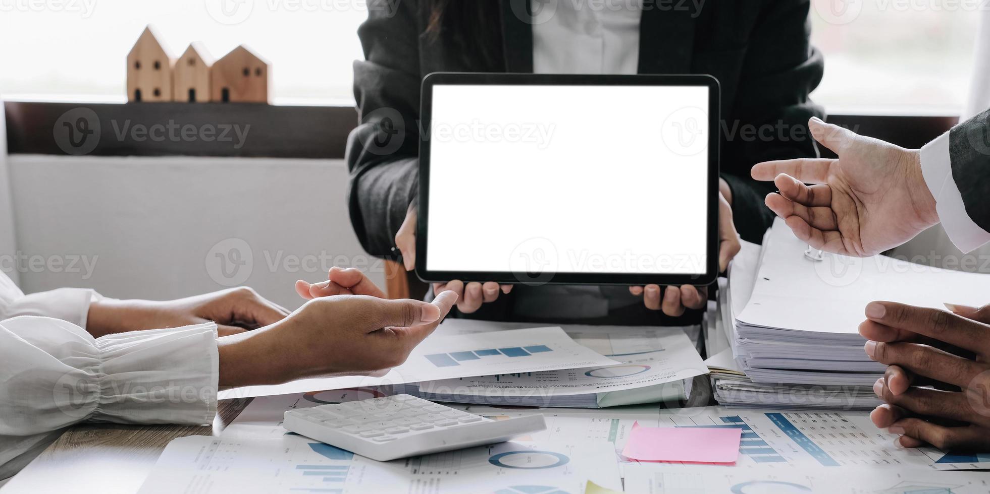 Two businesswomen meet in a meeting room for a business consultation, using a laptop computer and tablet. mockup of a laptop with a blank screen photo