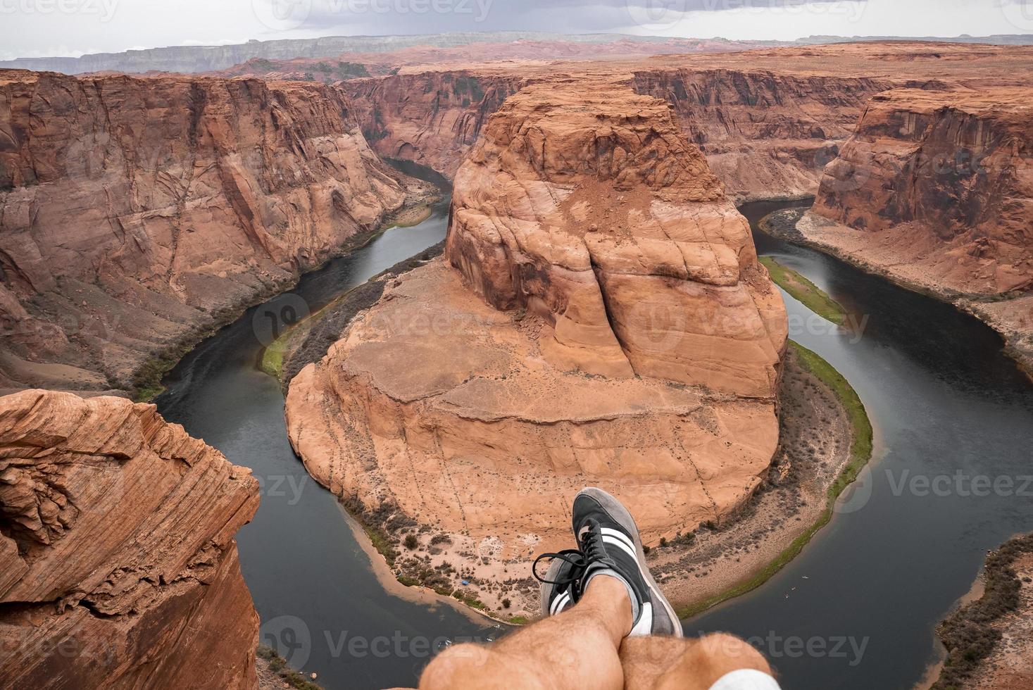 Low Section Of  Man Sitting Above Horseshoe Bend photo