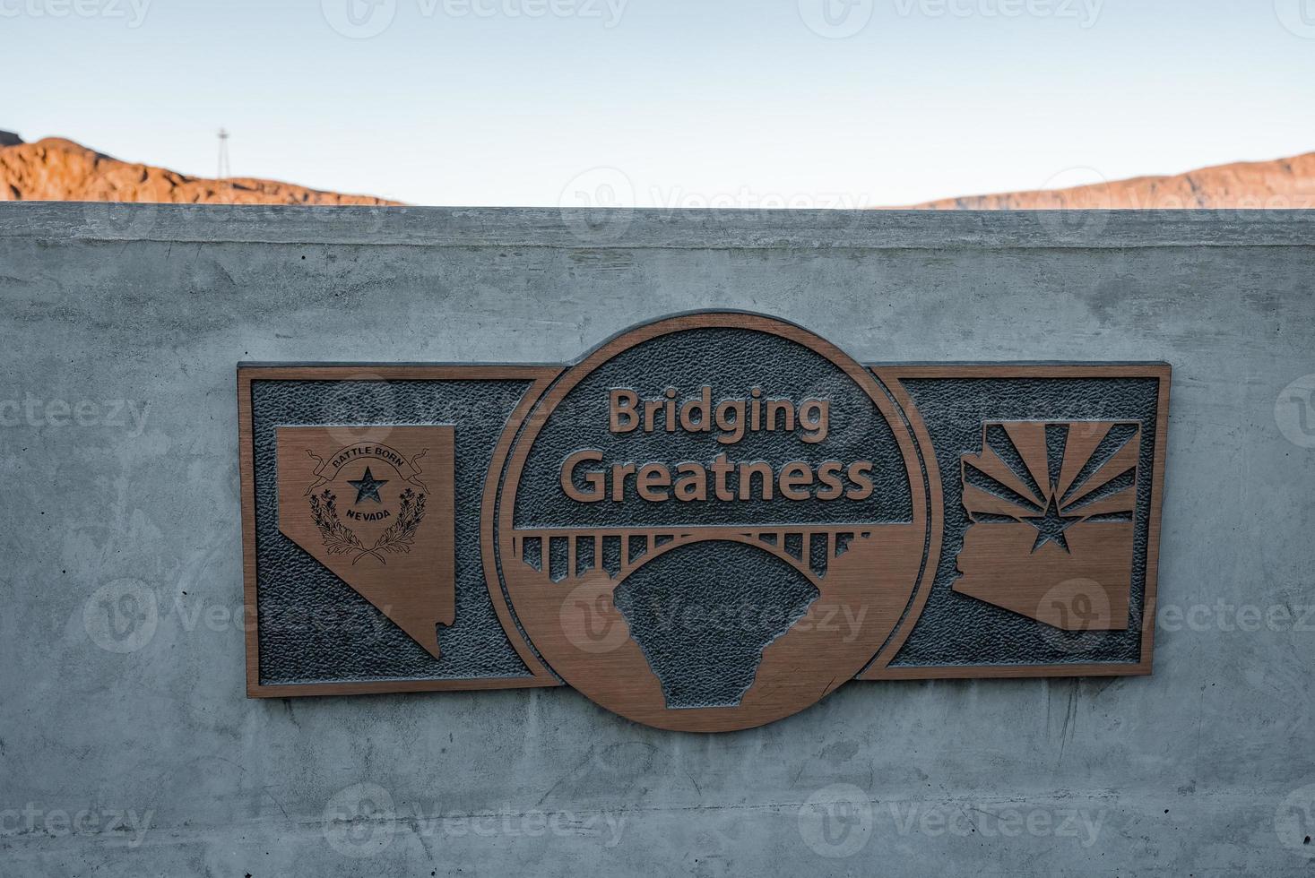 Bronze Plaque With Bridging Greatness Text On Wall photo