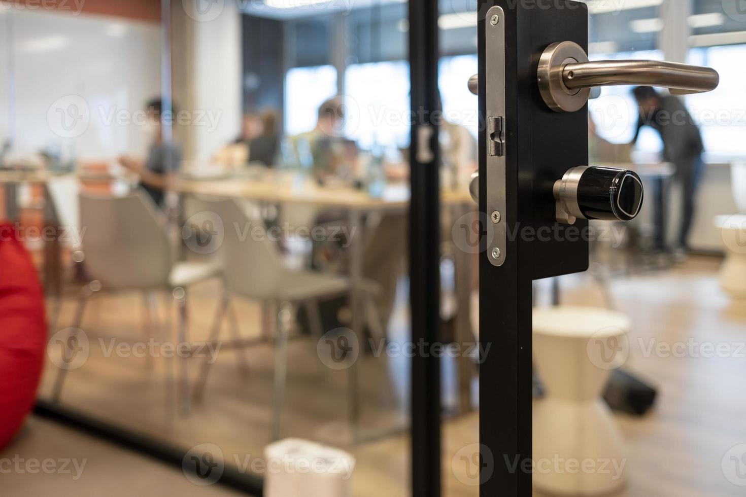 Open door to a coworking space, blurred silhouettes of people during a hackathon photo