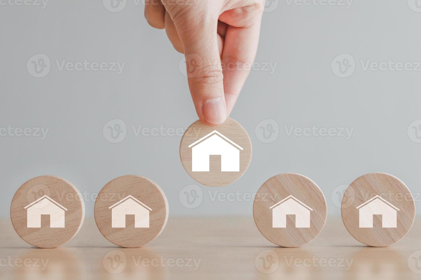 Real estate, Property investment and asset management concept. Hand choosing house icon on wood circle from many house. Decision to choose the best property with your right. Choosing suitable housing. photo