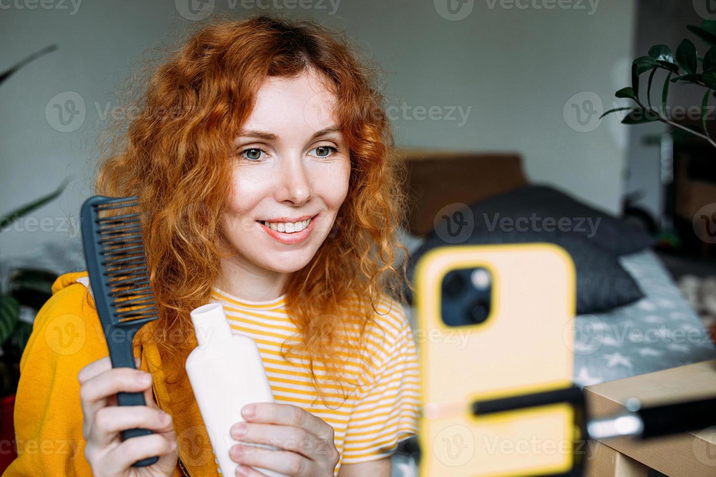 Red haired woman blogger broadcasts live reviews of beauty products for hair photo