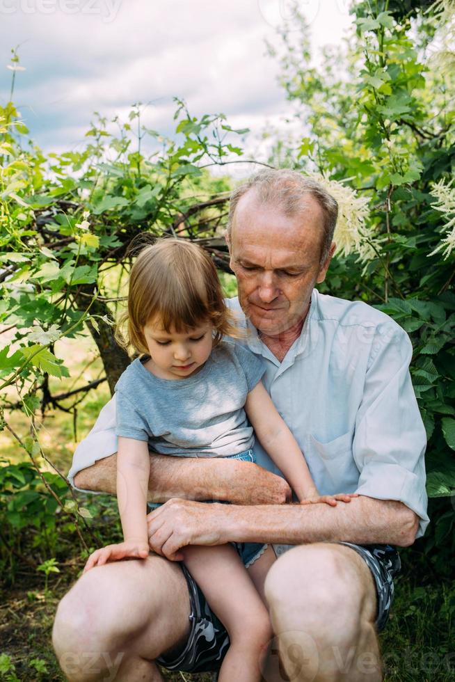 una niña abraza a su abuelo en un paseo al aire libre en verano. foto