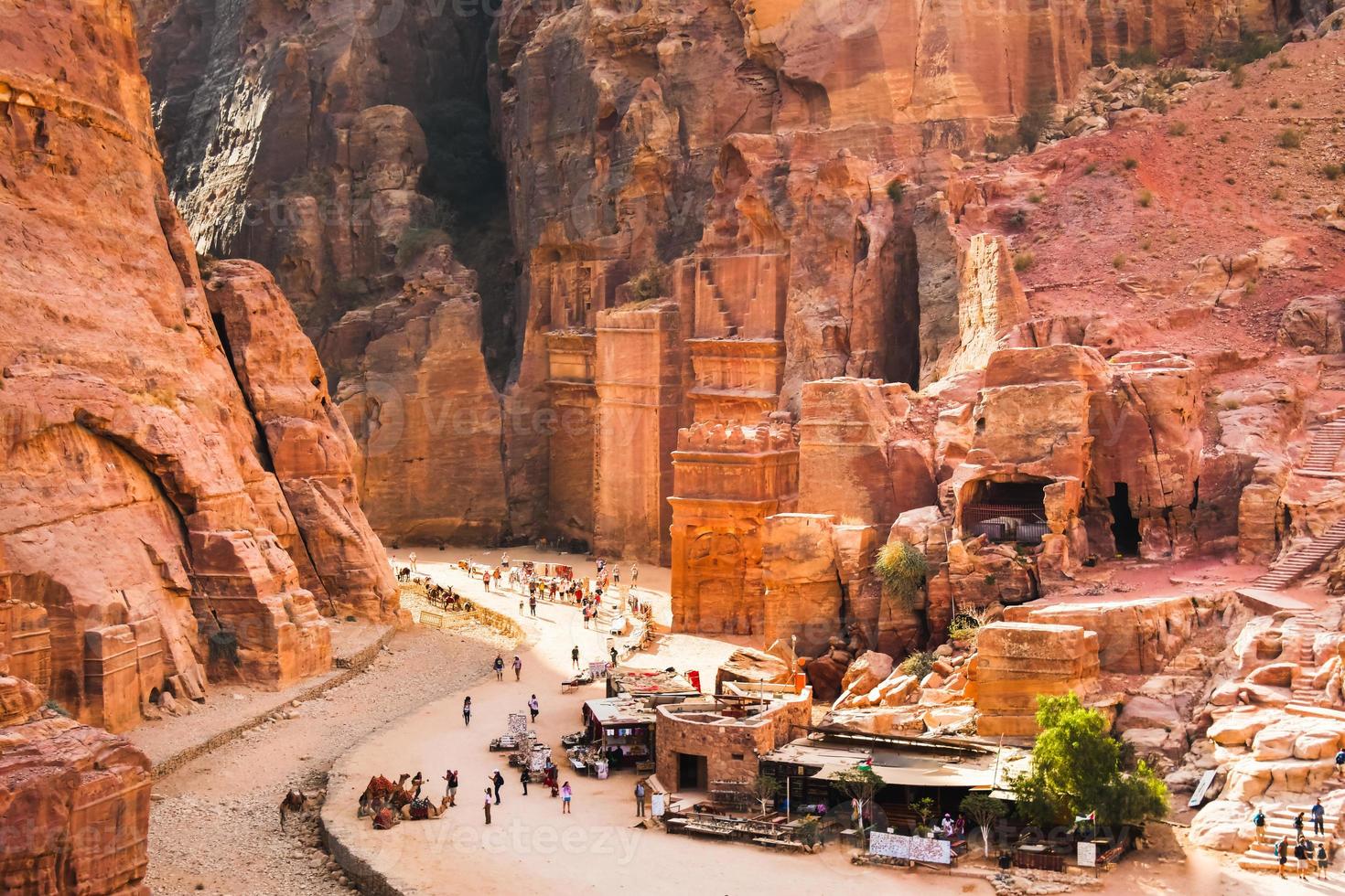 Tourist walk by caves of tombs in ancient city of Petra, Jordan. It is know as the Loculi. Petra has led to its designation as UNESCO World Heritage Site. photo