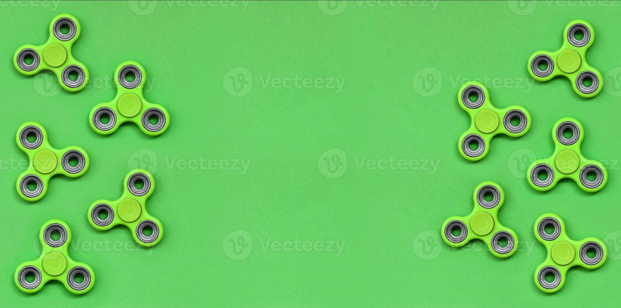 Many green fidget spinners lies on texture background of fashion pastel green color paper in minimal concept photo