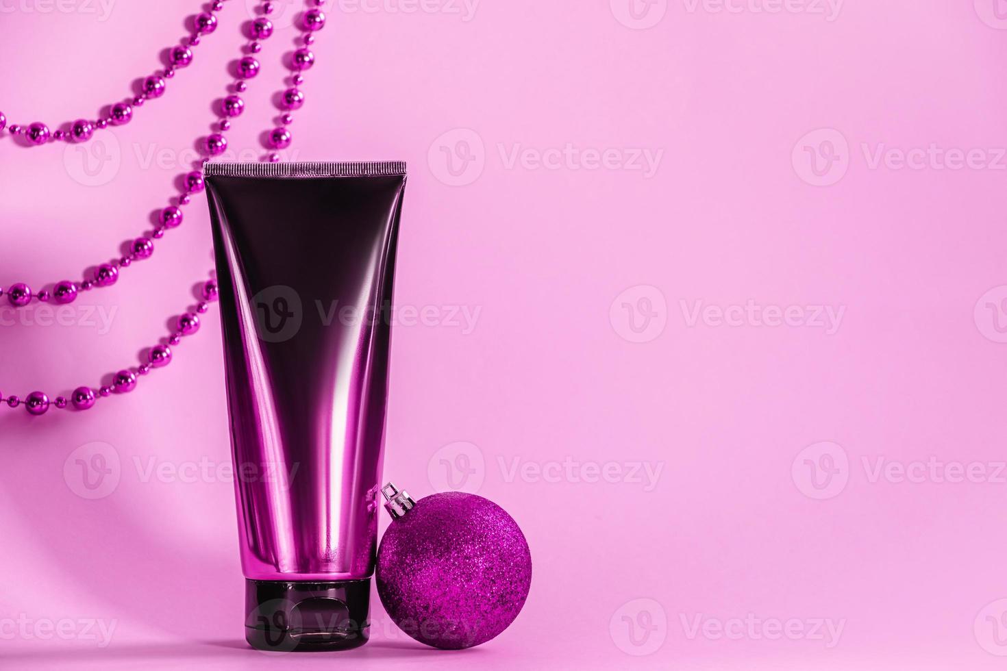 Stylish plastic bottle of cosmetics on pink background. Skin care cream and holiday decorations. photo