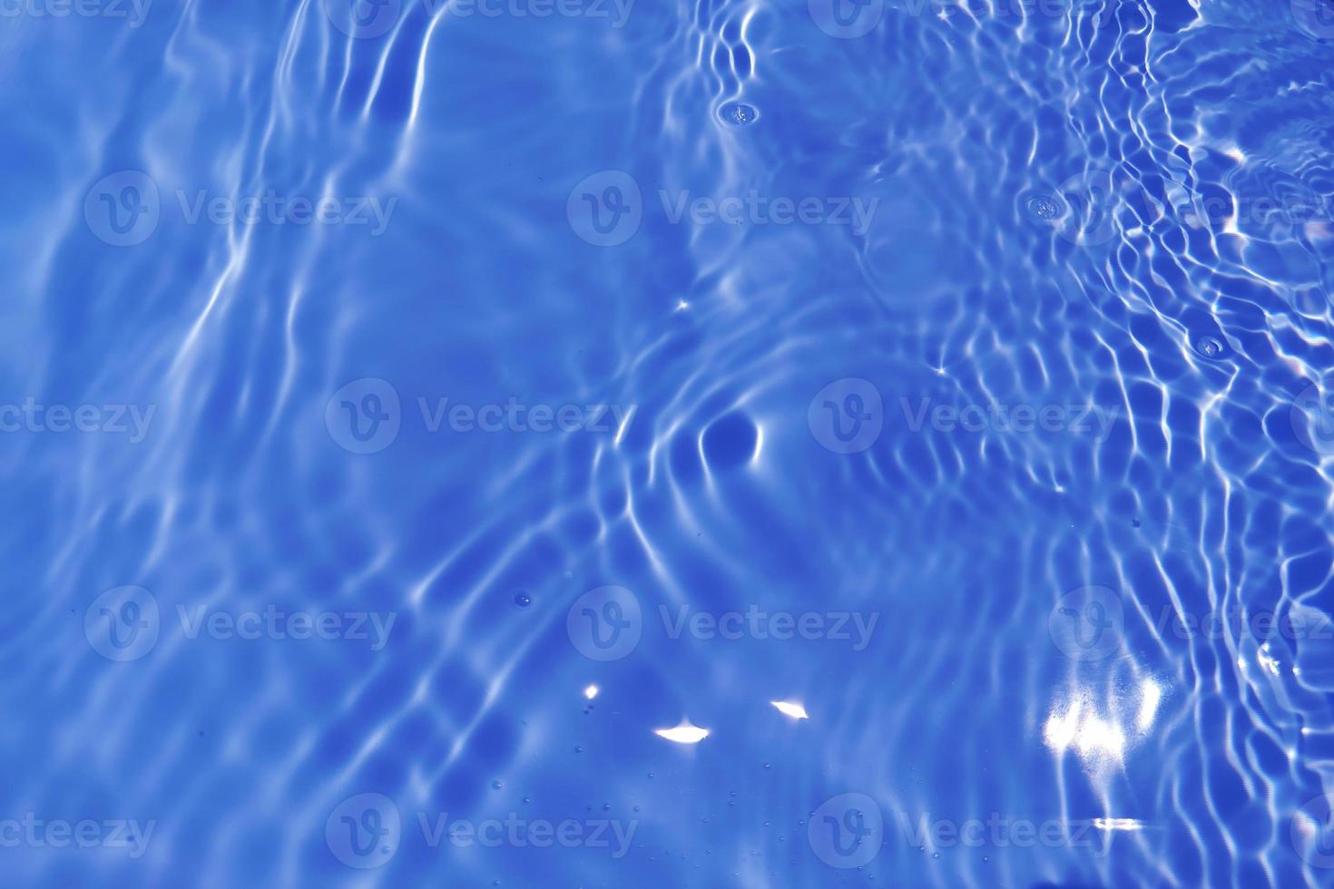 Defocus blurred transparent blue colored clear calm water surface texture with splashes and bubbles. Trendy abstract nature background. Water waves in sunlight with copy space. Blue watercolor shining photo