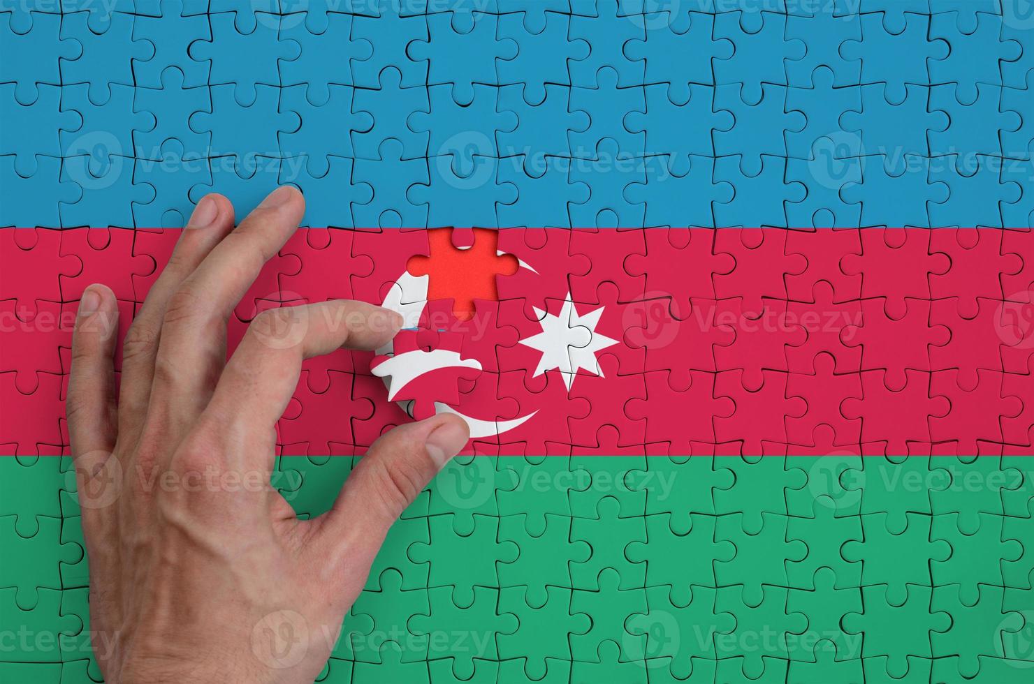 Azerbaijan flag is depicted on a puzzle, which the man's hand completes to fold photo