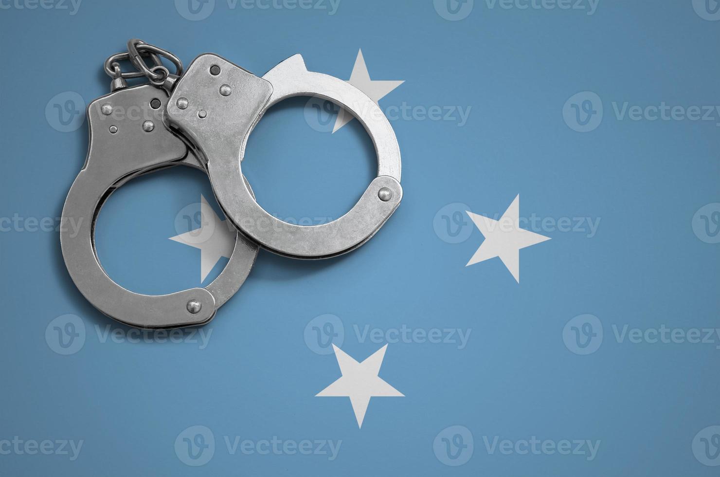 Micronesia flag and police handcuffs. The concept of crime and offenses in the country photo