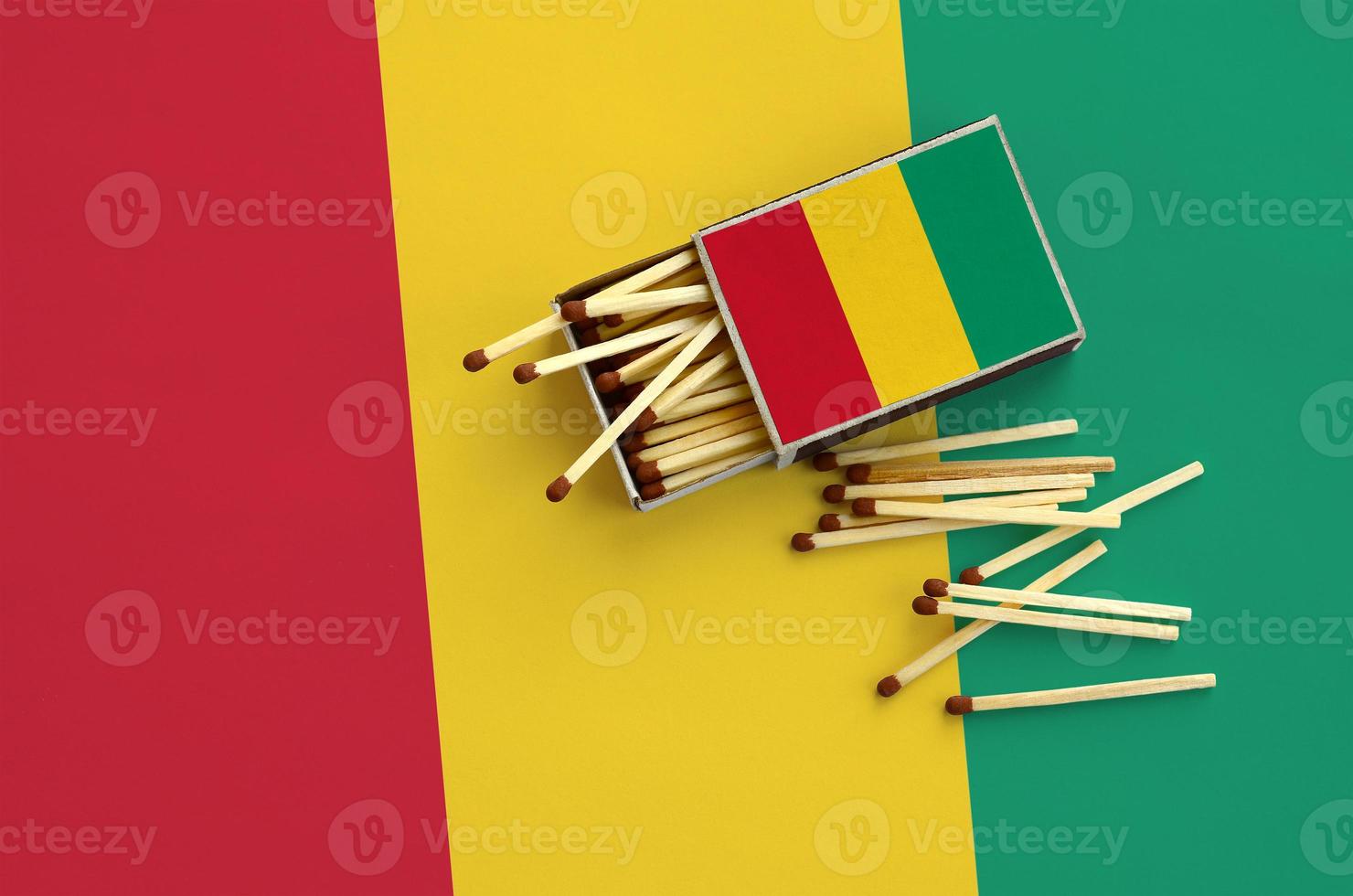 Guinea flag is shown on an open matchbox, from which several matches fall and lies on a large flag photo