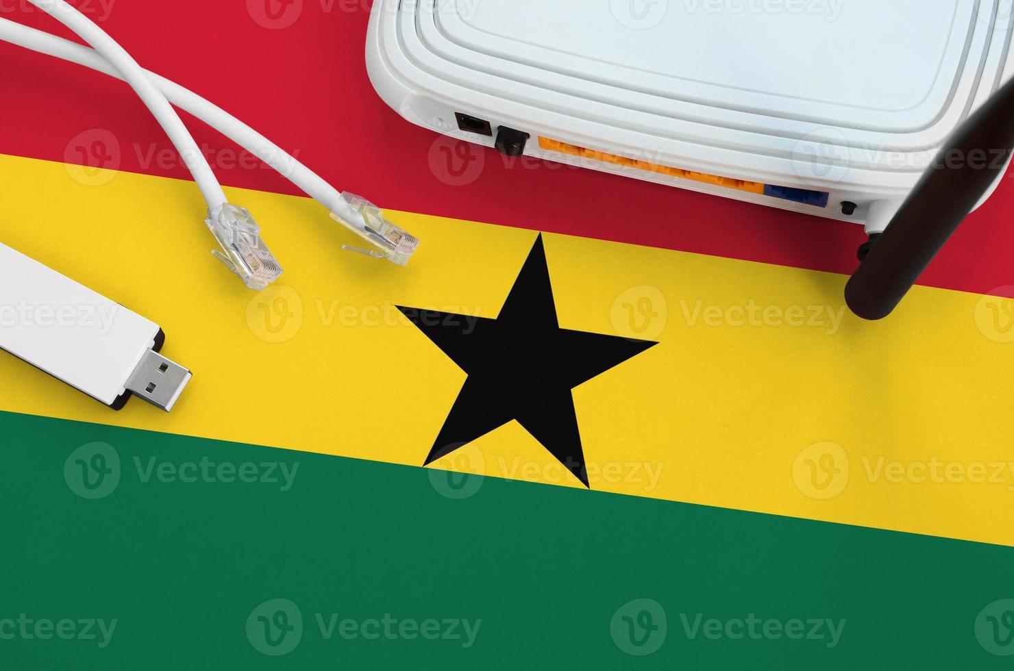 Ghana flag depicted on table with internet rj45 cable, wireless usb wifi adapter and router. Internet connection concept photo