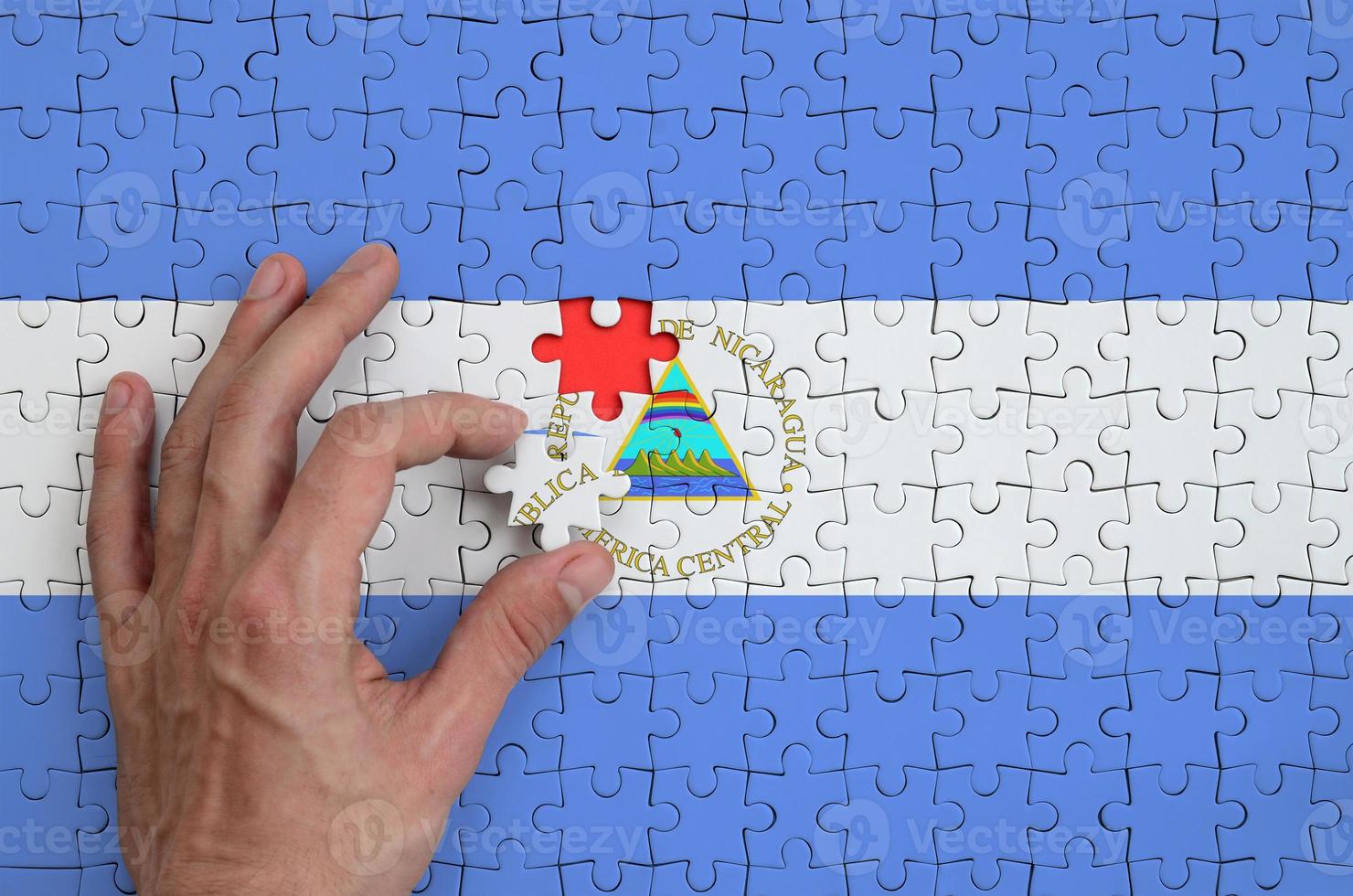 Nicaragua flag is depicted on a puzzle, which the man's hand completes to fold photo