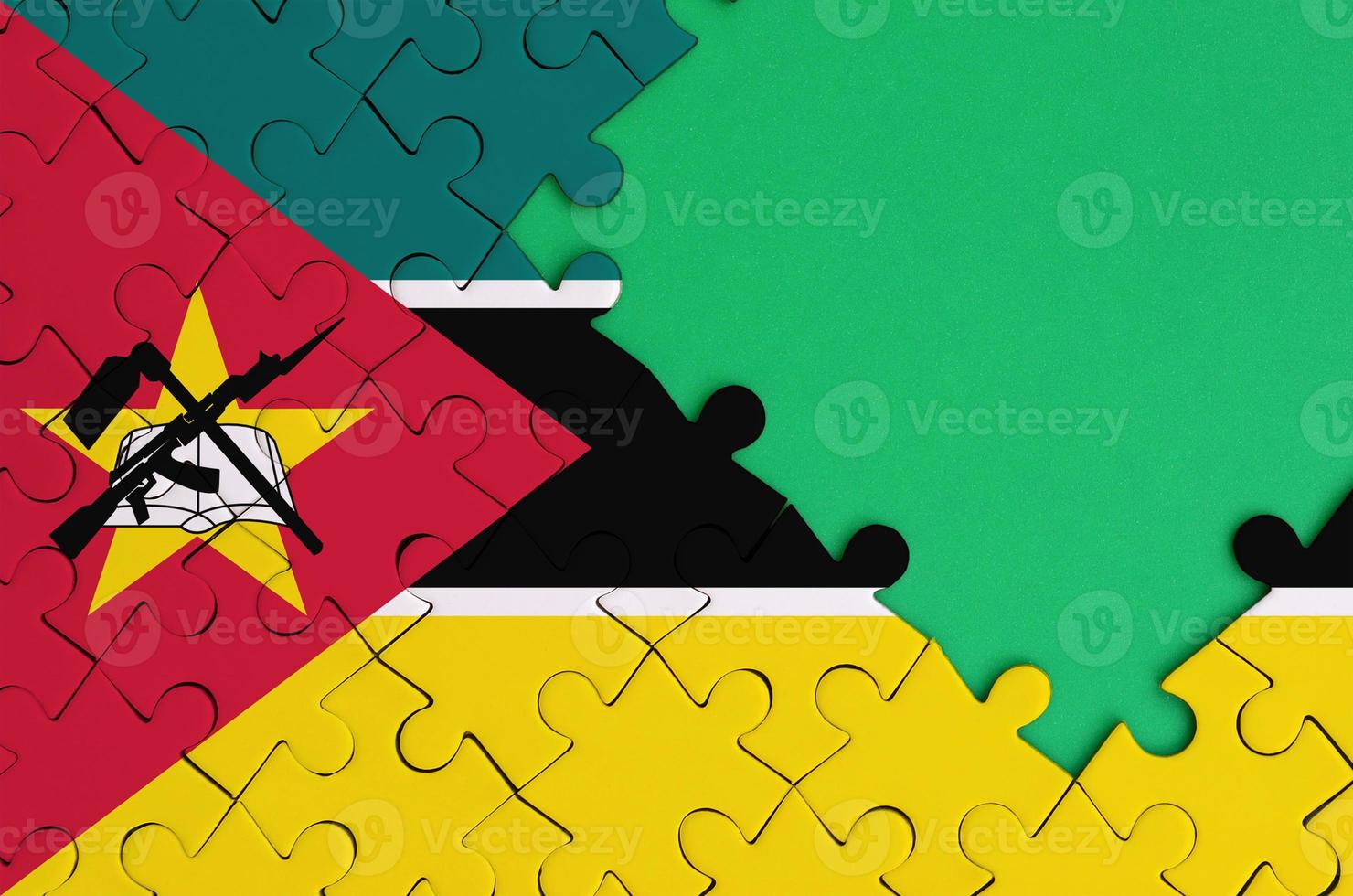 Mozambique flag is depicted on a completed jigsaw puzzle with free green copy space on the right side photo