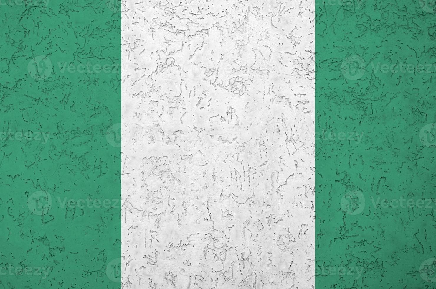 Nigeria flag depicted in bright paint colors on old relief plastering wall. Textured banner on rough background photo