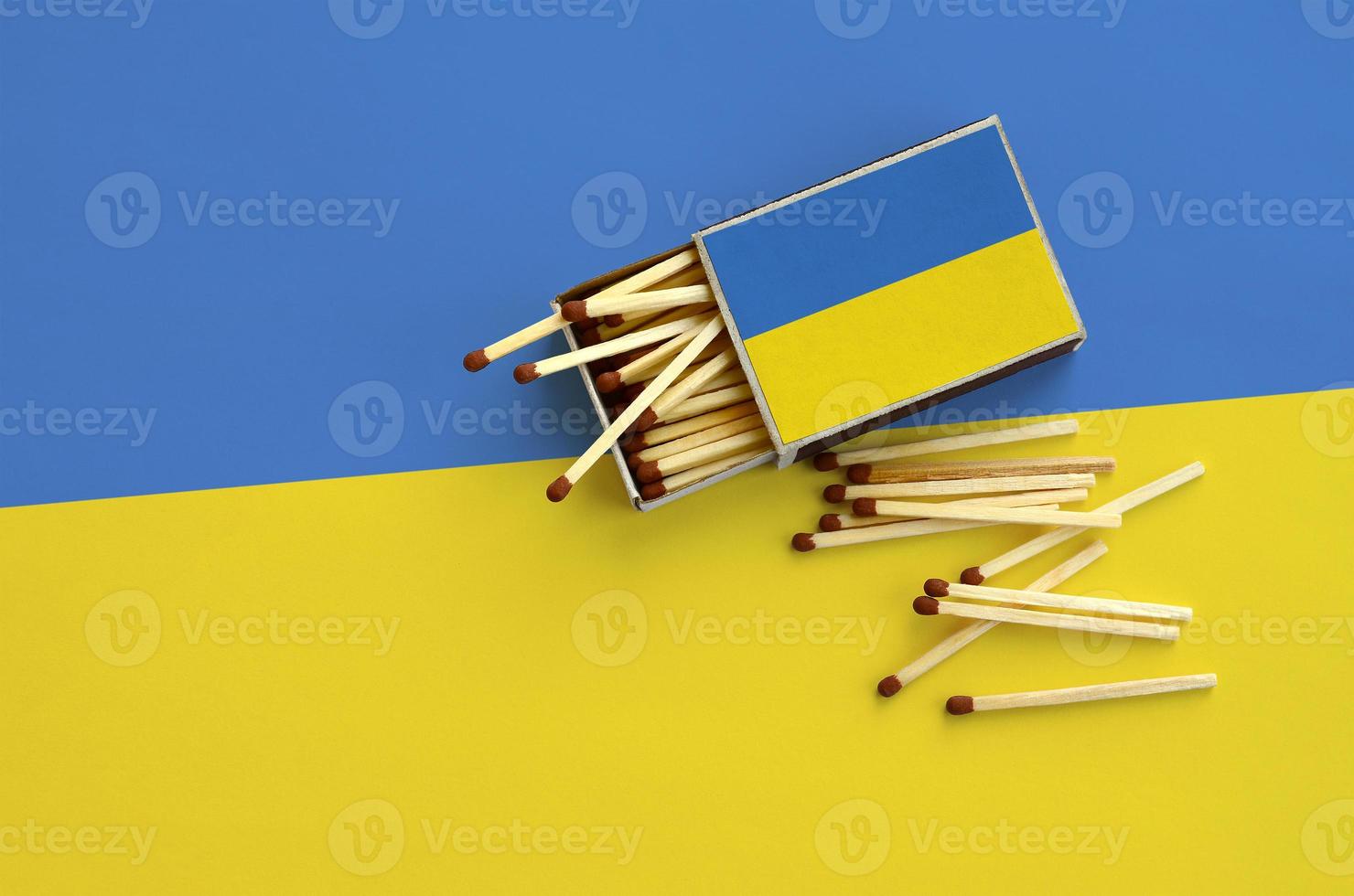 la bandera de ucrania se muestra en una caja de cerillas abierta, de la que caen varias cerillas y se encuentra en una bandera grande foto
