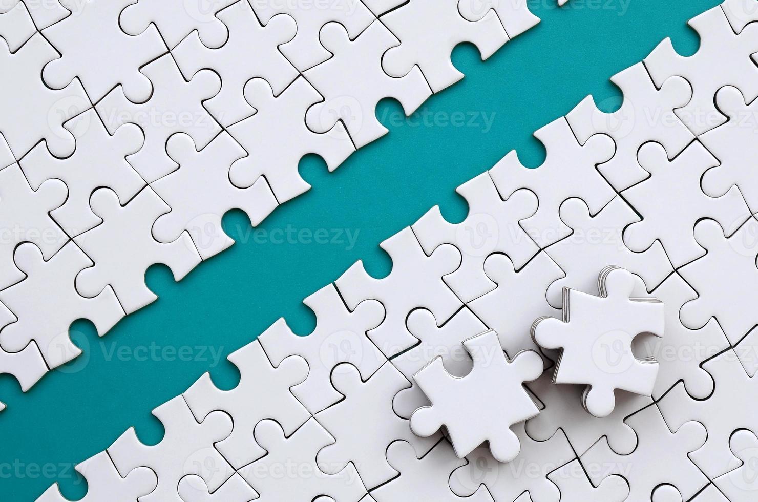 The blue path is laid on the platform of a white folded jigsaw puzzle. The missing elements of the puzzle are stacked nearby. Texture image with space for text photo