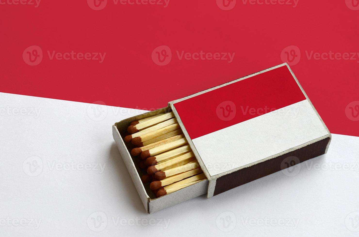 Monaco flag is shown in an open matchbox, which is filled with matches and lies on a large flag photo