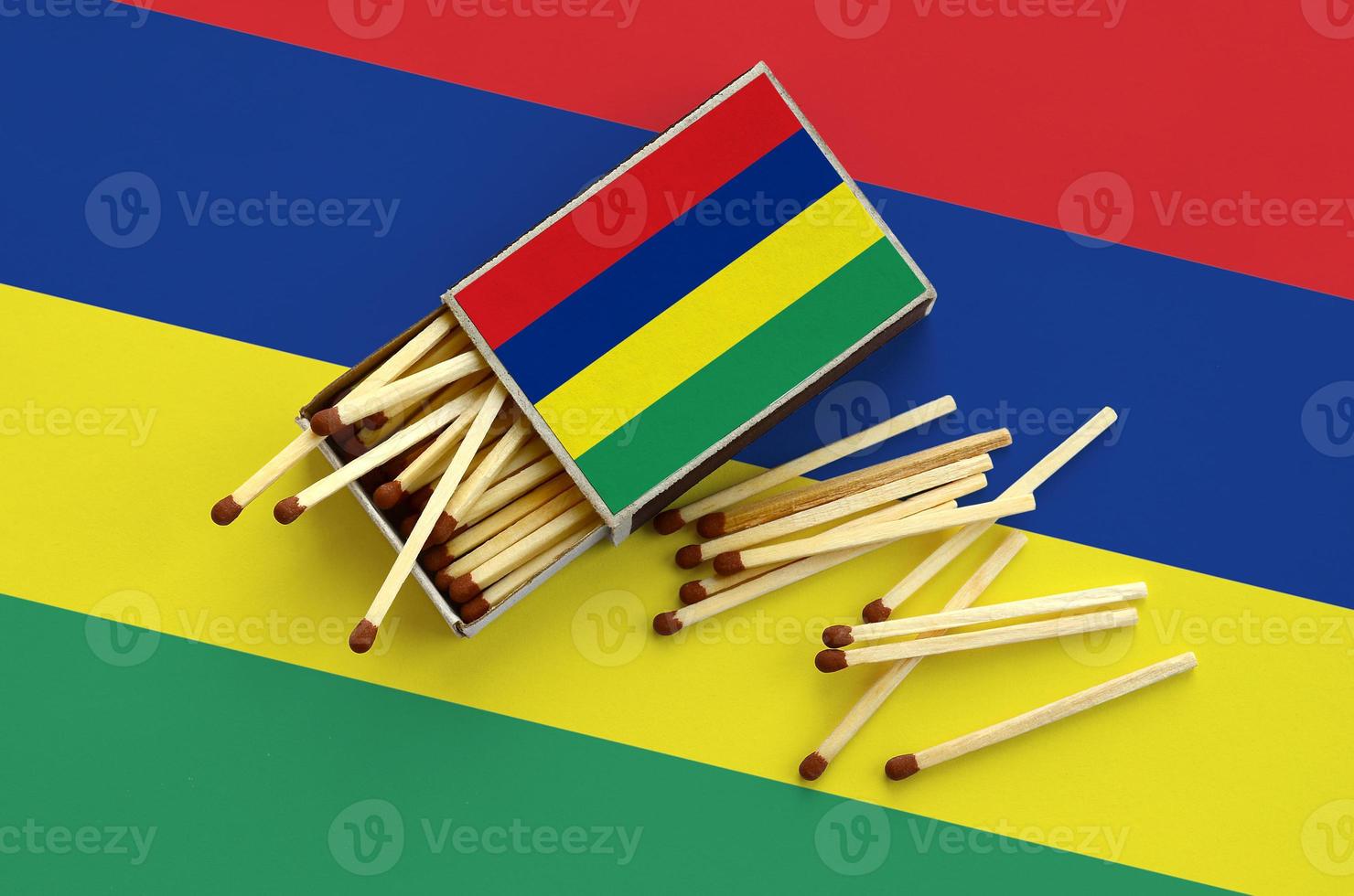 Mauritius flag is shown on an open matchbox, from which several matches fall and lies on a large flag photo