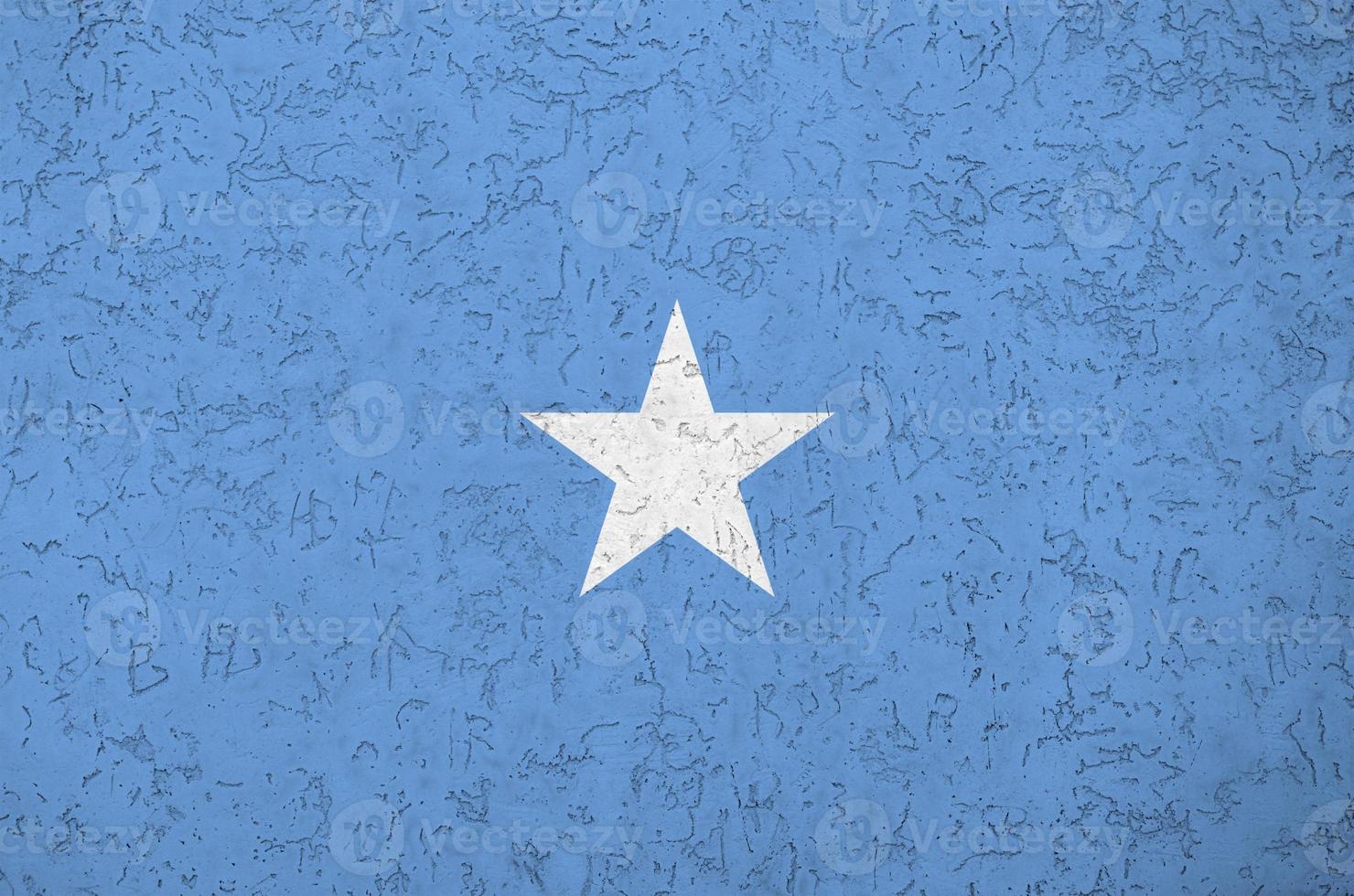Somalia flag depicted in bright paint colors on old relief plastering wall. Textured banner on rough background photo