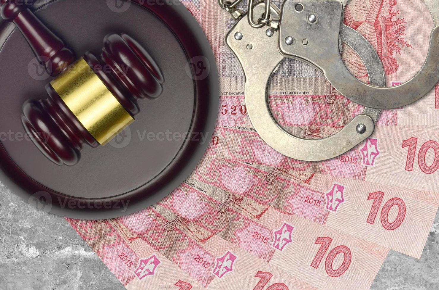 10 Ukrainian hryvnias bills and judge hammer with police handcuffs on court desk. Concept of judicial trial or bribery. Tax avoidance photo