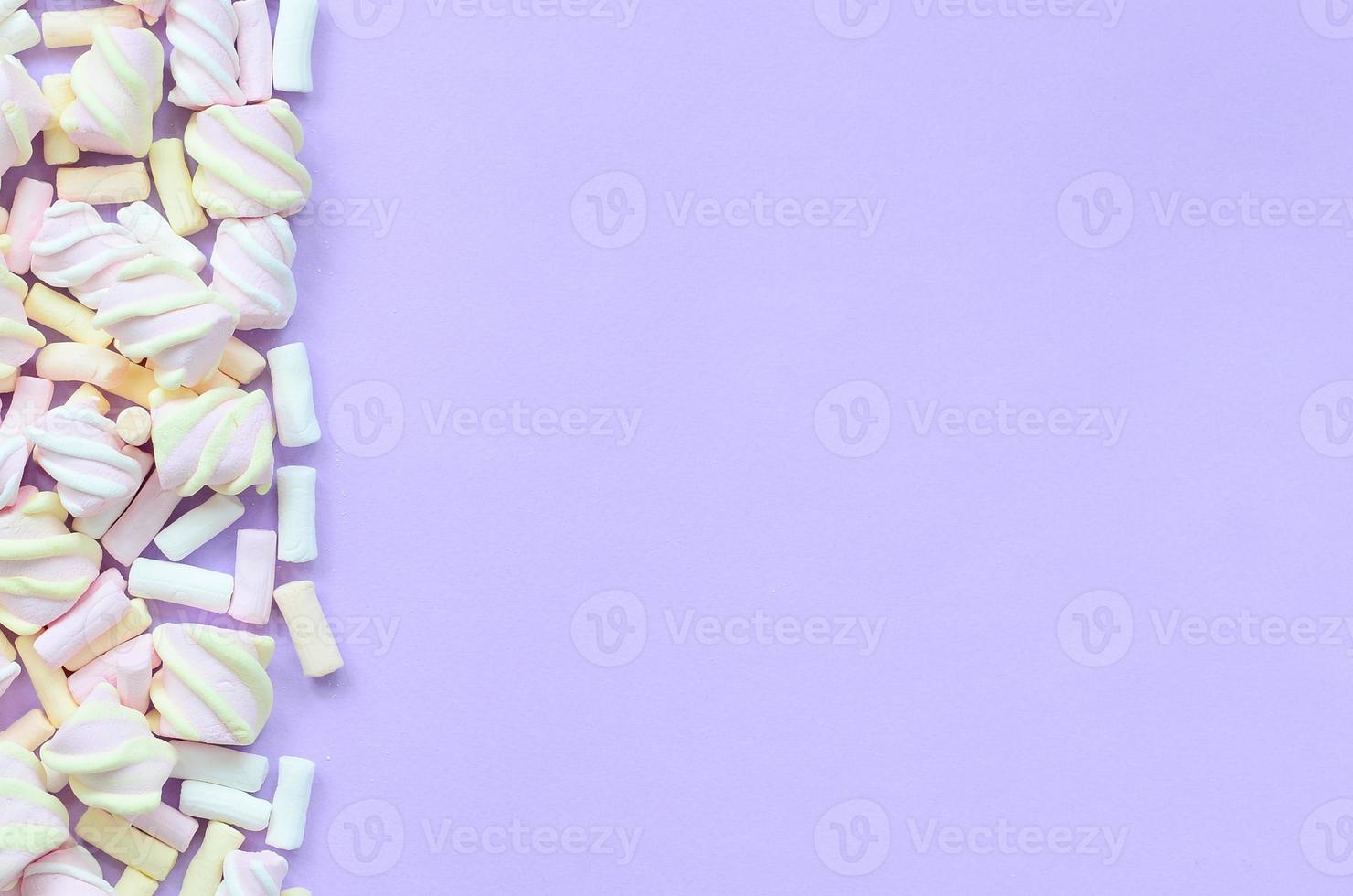 Colorful marshmallow laid out on violet paper background. pastel creative texture. minimal photo