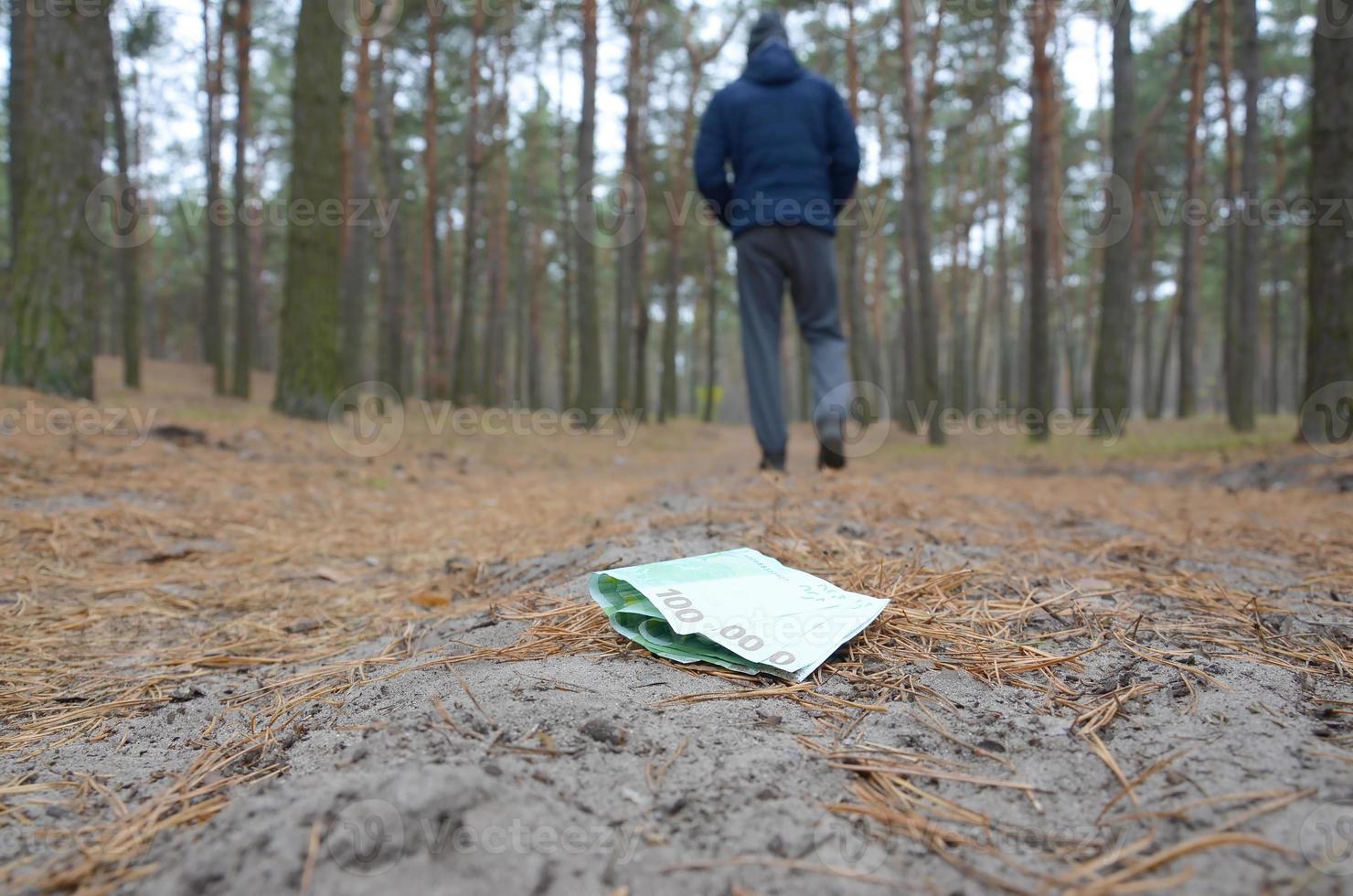 Young man loses his euro money bills on Russian autumn fir wood path. Carelessness and losing money concept photo
