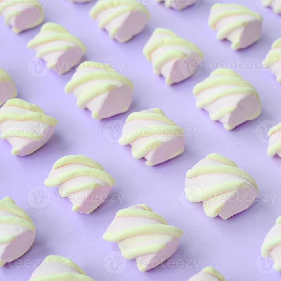 Colorful marshmallow laid out on violet paper background. pastel creative textured pattern. Perspective macro shot photo