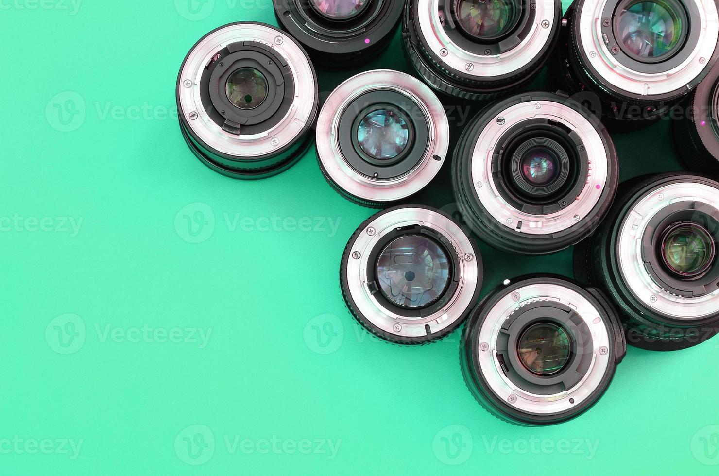 Several photographic lenses lie on a bright turquoise background. Copy space photo