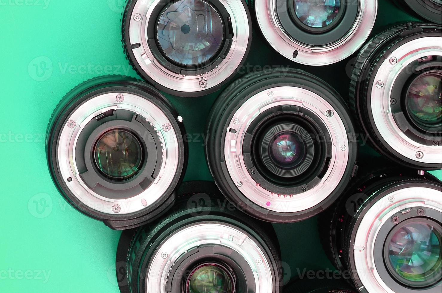 Several photographic lenses lie on a bright turquoise background. Copy space photo