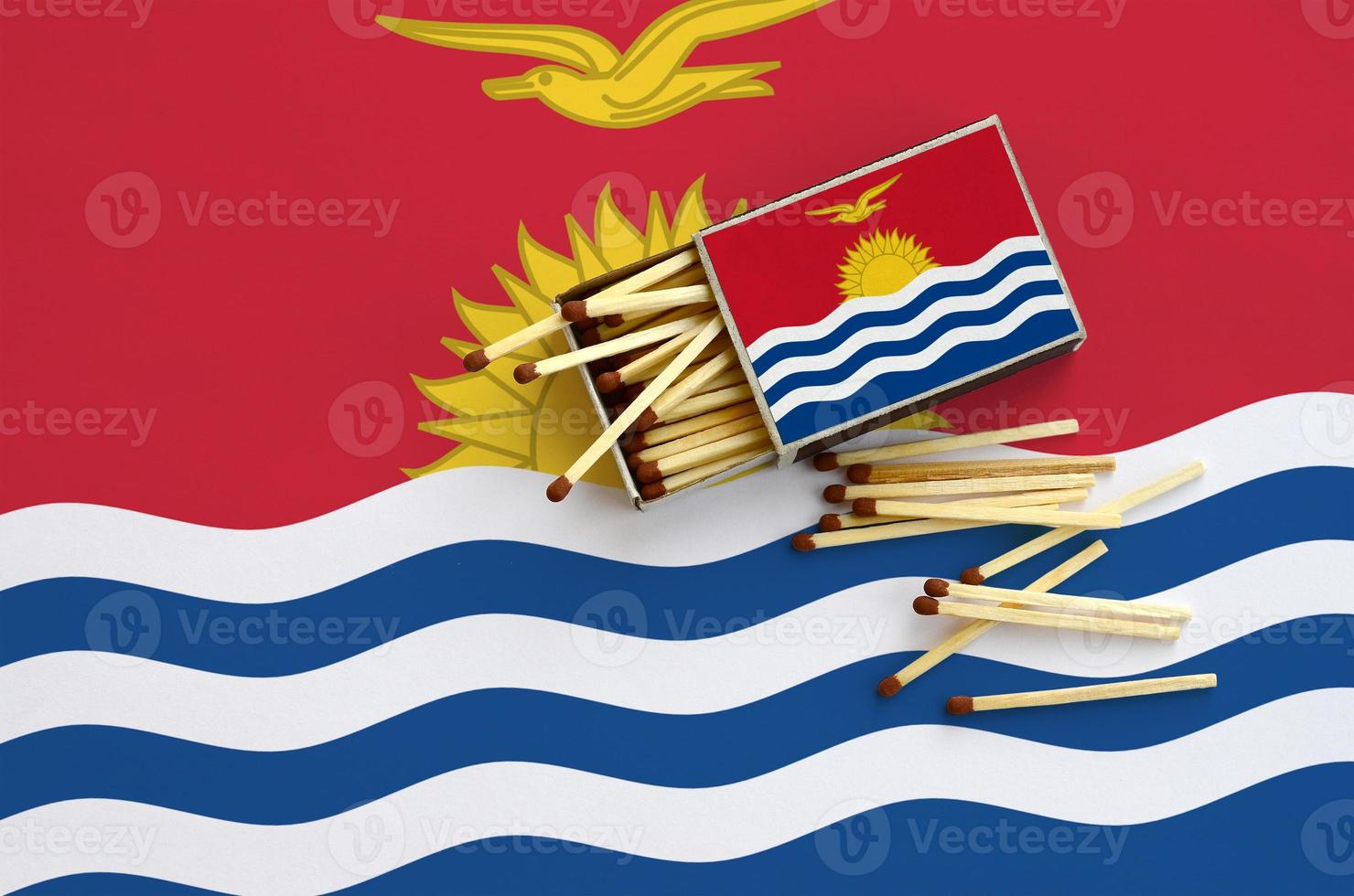 Kiribati flag is shown on an open matchbox, from which several matches fall and lies on a large flag photo