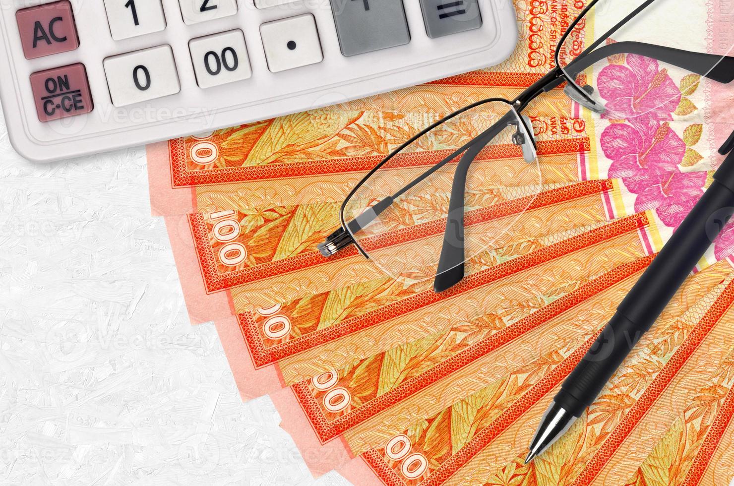 100 Sri Lankan rupees bills fan and calculator with glasses and pen. Business loan or tax payment season concept photo