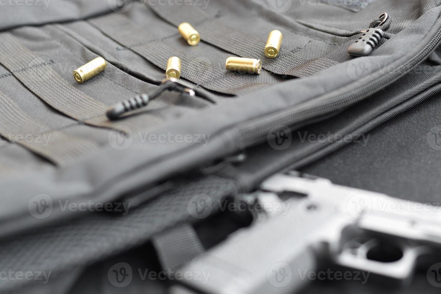 9mm bullets and pistol lie on a black tactical backpack photo