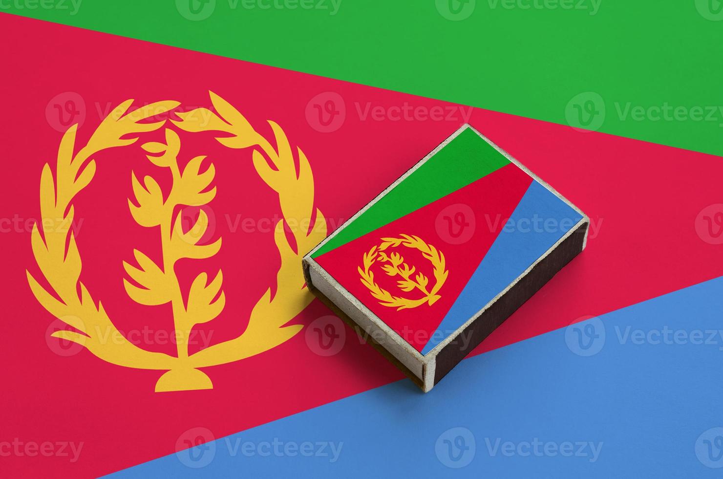 Eritrea flag is pictured on a matchbox that lies on a large flag photo