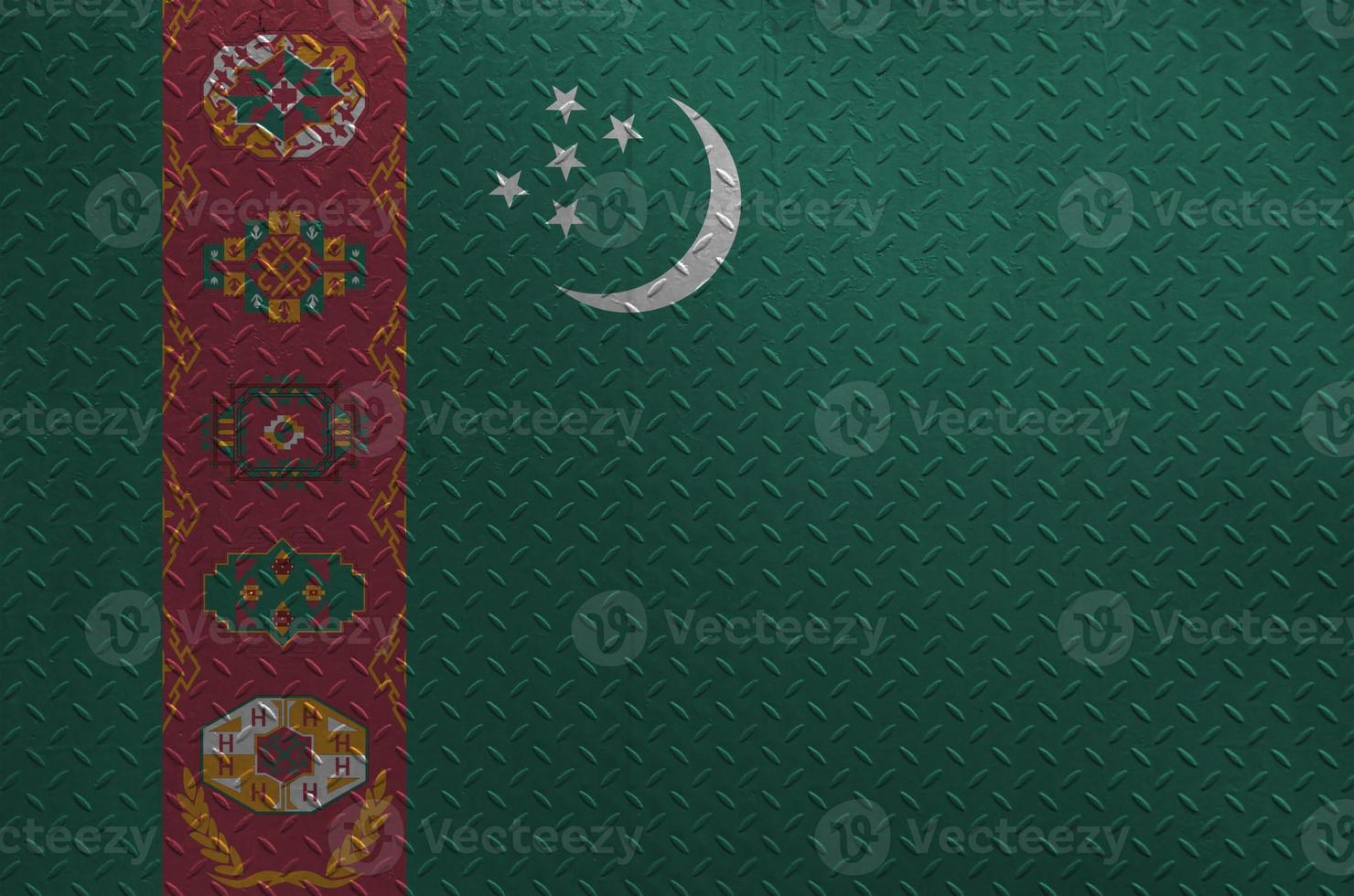 Turkmenistan flag depicted in paint colors on old brushed metal plate or wall closeup. Textured banner on rough background photo