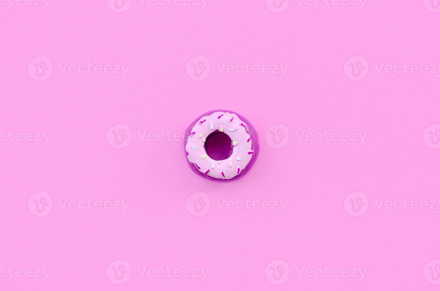 Single small plastic donut lies on a pastel colorful background. Flat lay minimal composition. Top view photo