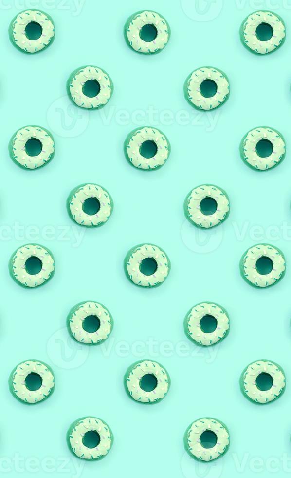 Many small plastic donuts lies on a pastel colorful background. Flat lay minimal pattern. Top view photo