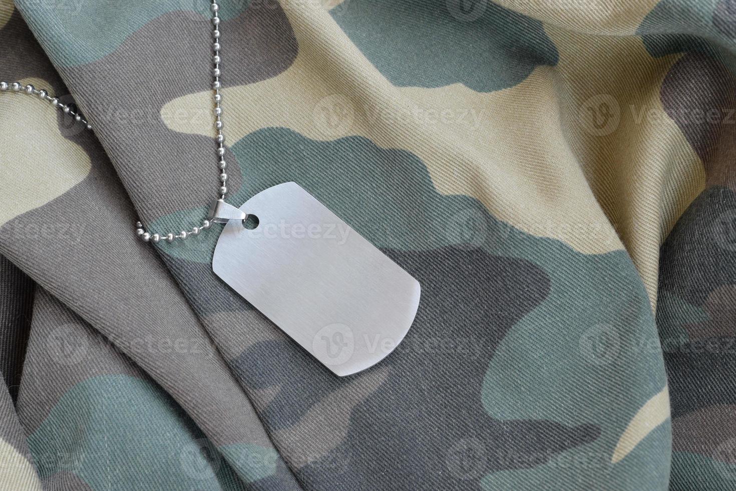 Cuentas militares plateadas con etiqueta de perro en uniforme de fatiga de camuflaje foto