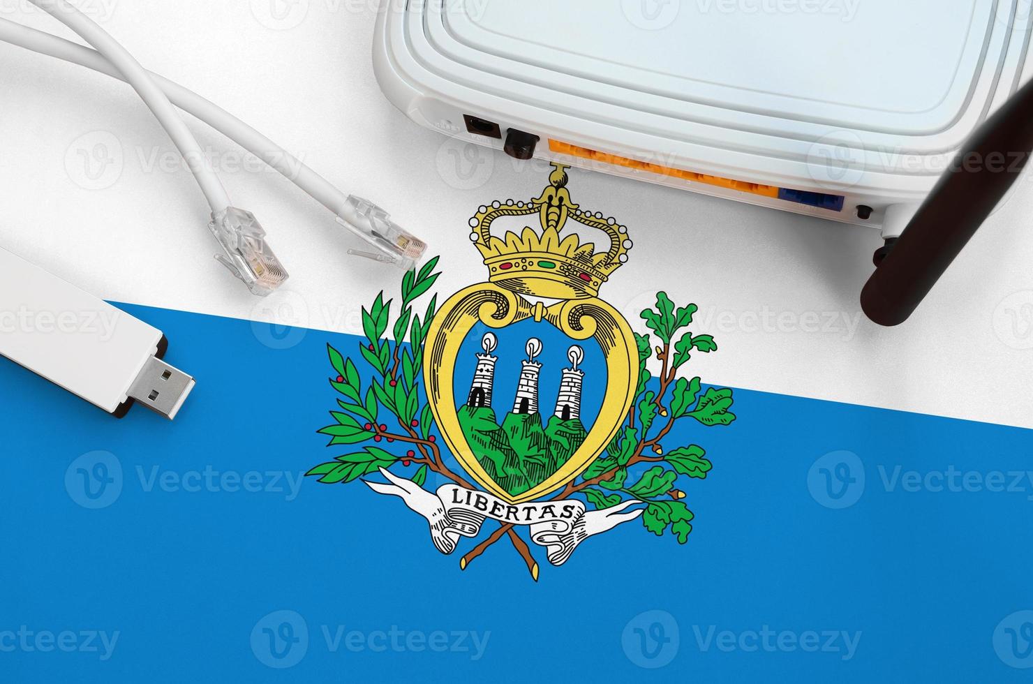 San Marino flag depicted on table with internet rj45 cable, wireless usb wifi adapter and router. Internet connection concept photo
