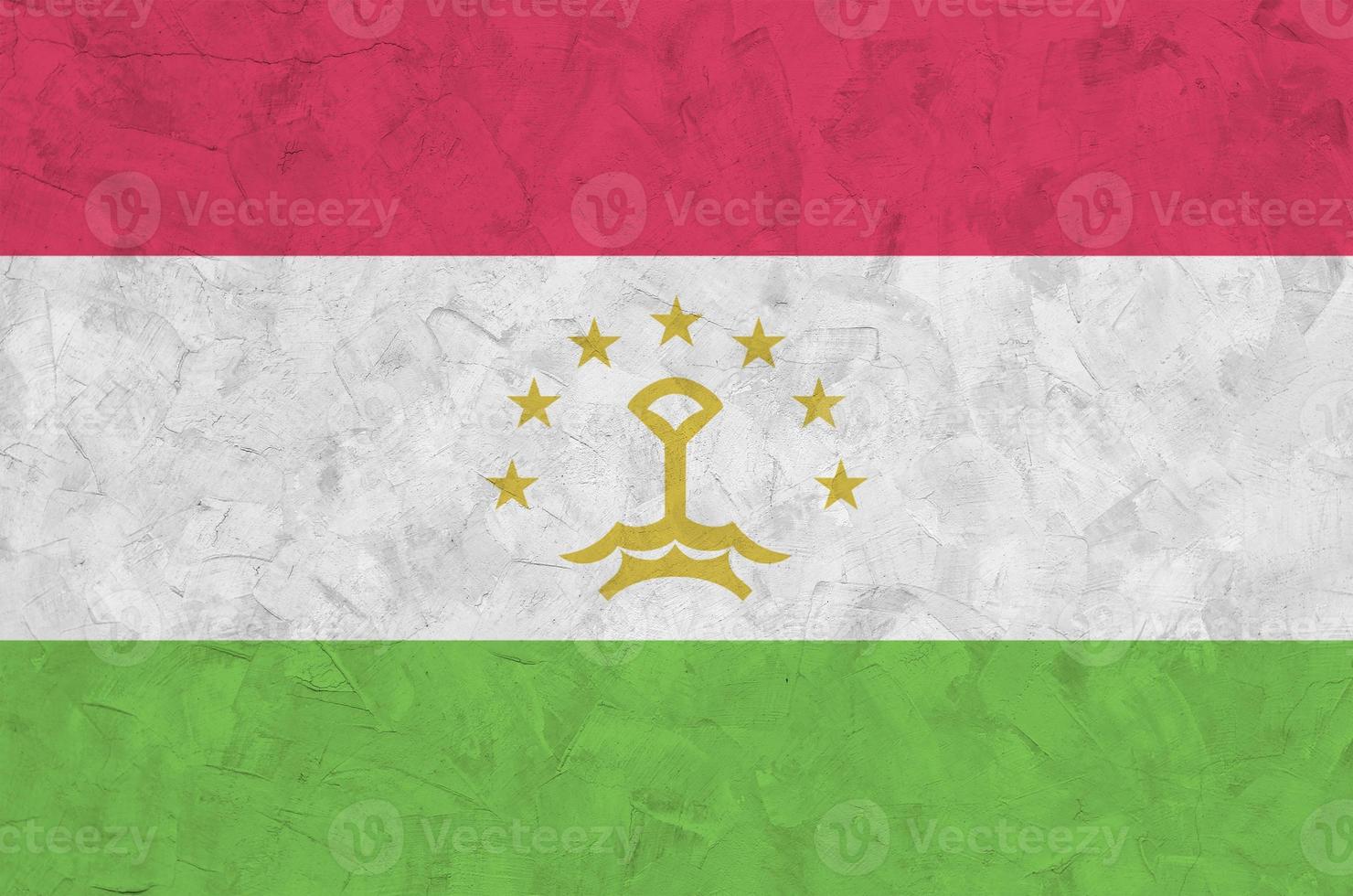 Tajikistan flag depicted in bright paint colors on old relief plastering wall. Textured banner on rough background photo