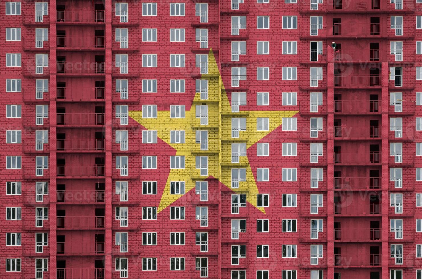 bandera de vietnam representada en colores de pintura en un edificio residencial de varios pisos en construcción. banner texturizado sobre fondo de pared de ladrillo foto