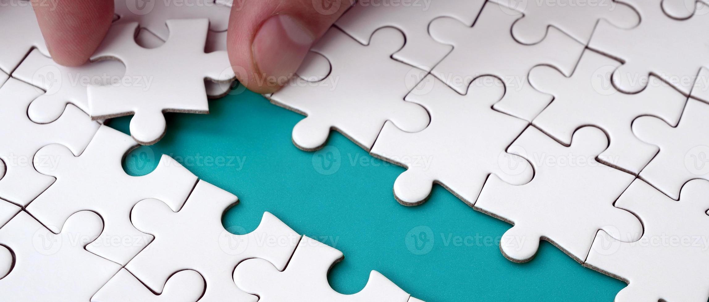 The human hand paves the way to the surface of the jigsaw puzzle, forming a blue space. The concept of overcoming the difficulties on the way to success photo