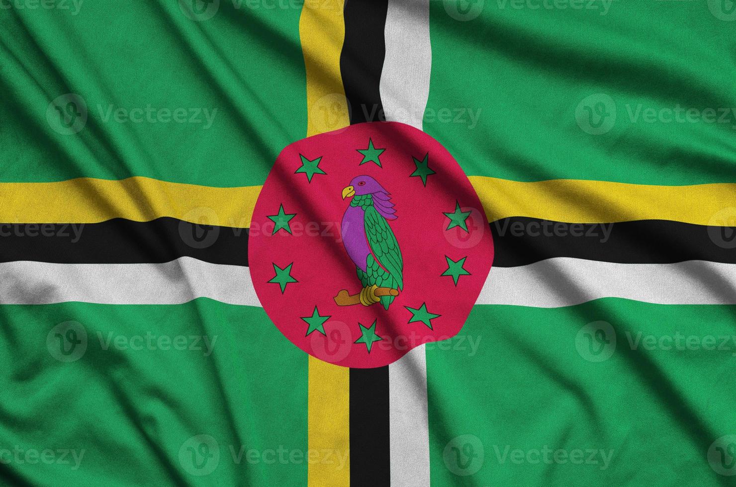 Dominica flag is depicted on a sports cloth fabric with many folds. Sport team banner photo
