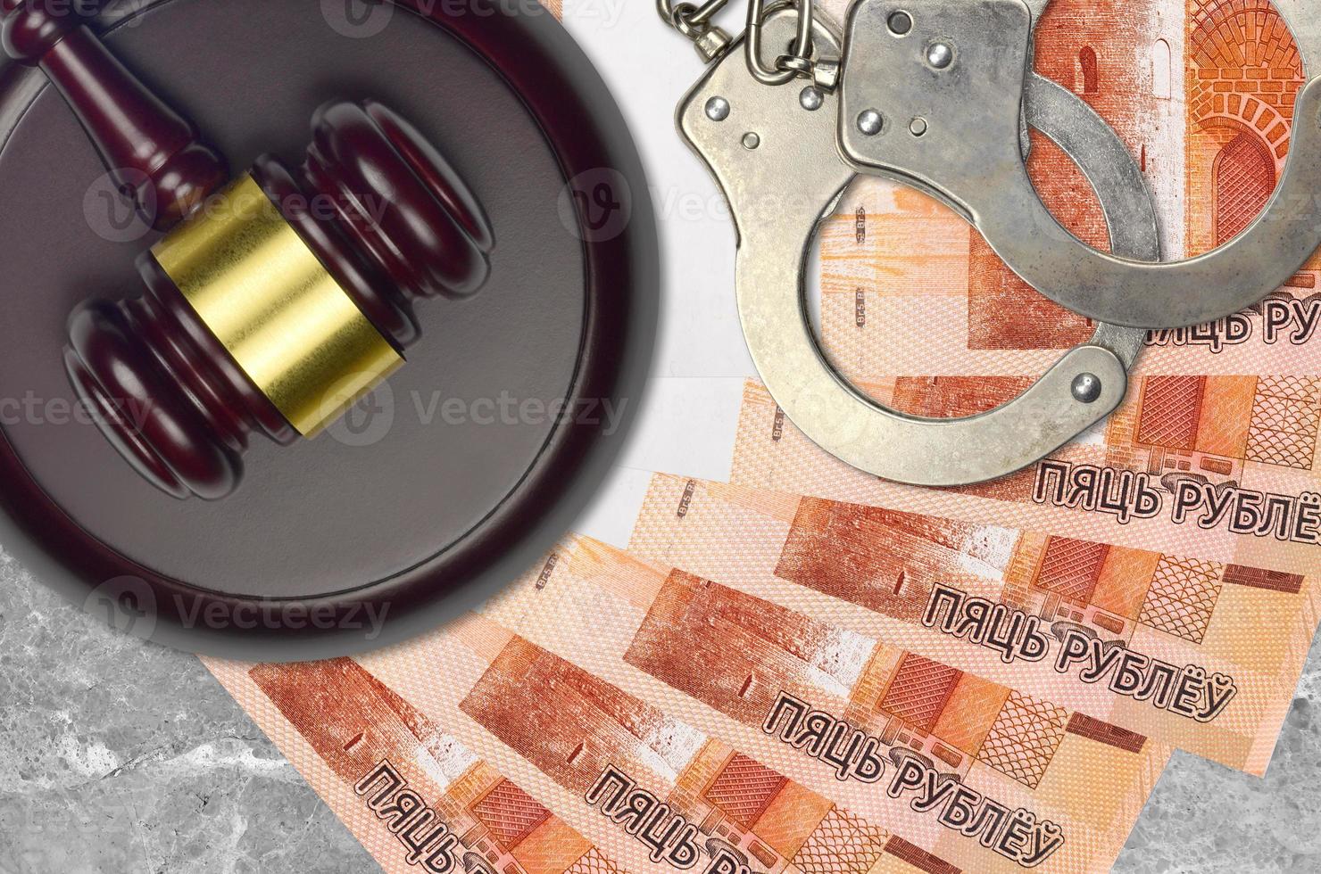 5 Belorussian rubles bills and judge hammer with police handcuffs on court desk. Concept of judicial trial or bribery. Tax avoidance photo