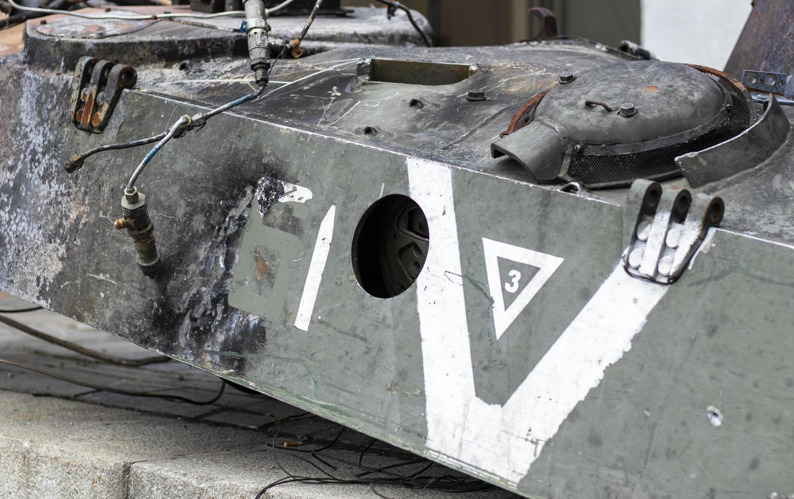 War in Ukraine. Destroyed tank with a torn off turret with a V on it. Broken and burned Russian tanks. Designation sign or symbol in white paint on the tank. Destroyed military equipment. photo